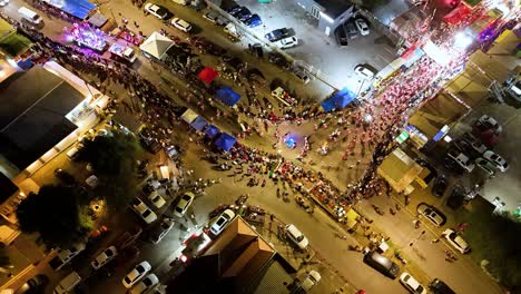 Drohnenansicht-Aus-Der-Vogelperspektive-über-Der-Parade-Bei-Nacht-Mit-Tänzern,-Die-Eine-Straßenbiegung-Umrunden