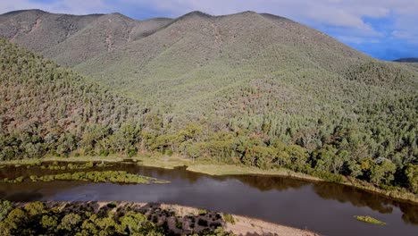 Reverse-aerial-shot-of-lower-Snowy-River-and-remote-mountain-range-in-Kosciuszko-National-Park,-New-South-Wales,-Australia