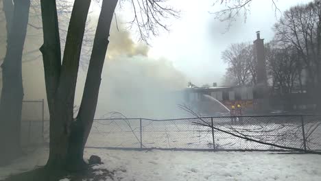 Derelict-School-and-Kindergarten-Building-with-Fire-Crew-Extinguishing-a-Fire-with-Billowing-Thick-Smoke-in-Cartierville,-Montréal,-Canada