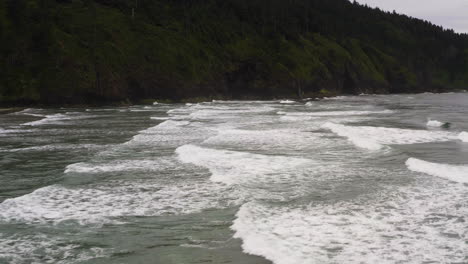 Long-rolling-waves-crash-across-the-waters-of-Cape-Lookout,-Oregon,-aerial-dolly