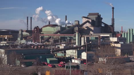Industrial-complex-in-Hamilton,-Ontario-with-smokestacks-against-blue-sky,-wide-shot