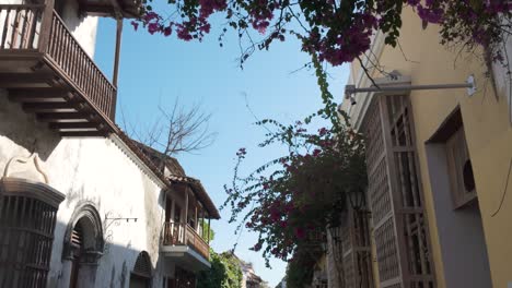 Walking-along-traditional-street-with-old-buildings-and-flowers-in-Cartagena,-Colombia