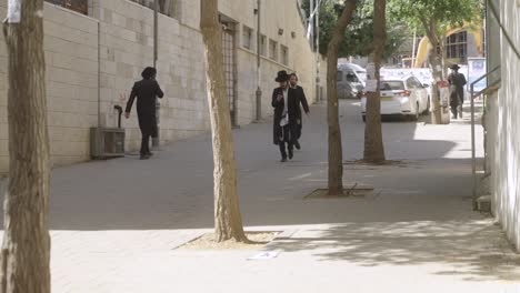 Hasidic-Jewish-people-walking-in-a-street-in-Jerusalem,-Israel