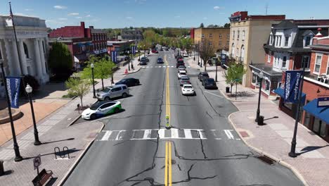 American-town-main-street-with-traffic,-people,-stores,-and-houses-on-bright-spring-day