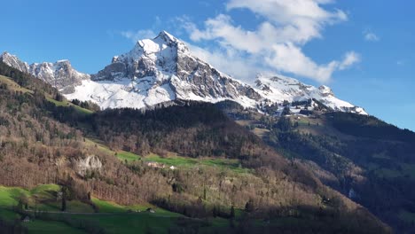 An-aerial-of-the-picturesque-snow-covered-mountain-peaks-of-Glarus-Nord,-Schweiz,-bordered-by-forests-at-lower-altitudes-devoid-of-snow,-the-concept-of-high-and-low-elevations-in-mountainous-regions