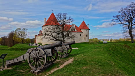 Toma-En-Primera-Persona-Caminando-Frente-A-Los-Cañones-Con-El-Museo-Del-Castillo-De-Bauska-Al-Fondo.