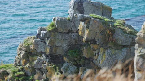 Withered-rocky-cliffs-covered-with-moss-and-grass-on-the-shore-of-the-fjord