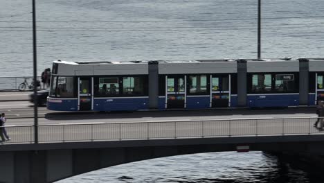 Tracking-drone-shot-of-Zurich-city-tram-crossing-a-bridge-on-Lake-Zurich