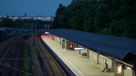 Escena-Crepuscular-En-Una-Estación-De-Tren-Suburbano-Con-Un-Pasajero-Solitario-Esperando