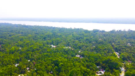 Small-African-alike-village-in-dense-forest-by-a-large-river,-aerial-360-degree-pan-right