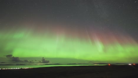 On-a-dark-winter-night,-a-tranquil-fjord-and-its'-coast-are-illuminated-by-the-enchanting-dance-of-the-Northern-Lights-in-this-timelapse-video