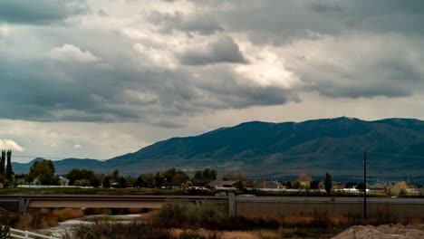 El-Tiempo-Del-Paisaje-Nublado-Pasa-Sobre-Una-Montaña,-Una-Carretera-Y-Una-Comunidad-Suburbana---Panorama