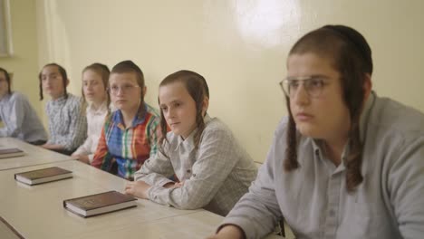 Estudiantes-Judíos-Ultraortodoxos-Con-Kipá-Aprendiendo-En-Clase-Escuchando-A-Su-Maestro,-De-Cerca