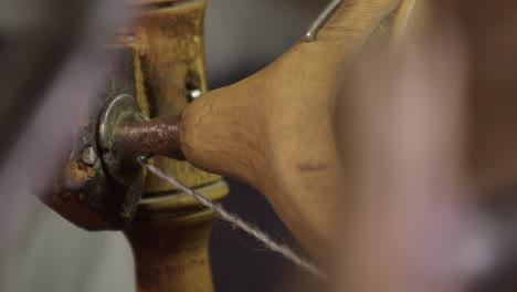 Closeup-bobbin-spool-detail-seen-through-antique-spinning-wheel-spokes