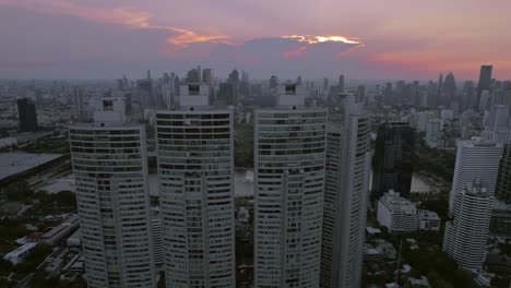 Hochhäuser-In-Bangkok-Bei-Sonnenuntergang,-Dämmerung,-Rückfahrdrohne