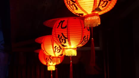 Jiufen-red-lanterns-swaying-gently-in-the-dark-night,-casting-a-warm-glow-against-the-dark-backdrop,-close-up-shot