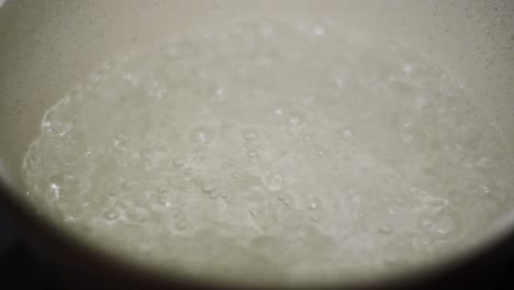 Boiling-water-close-up-shot-metallic-silver-rounded-pan-with-hot-bubbles-inside-static