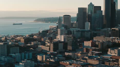 Eine-Dynamische-Luftaufnahme-Der-Skyline-Von-Seattle-Und-Der-Innenstadt-Neben-Dem-Puget-Sound-Und-Einem-Dunstigen-Horizont