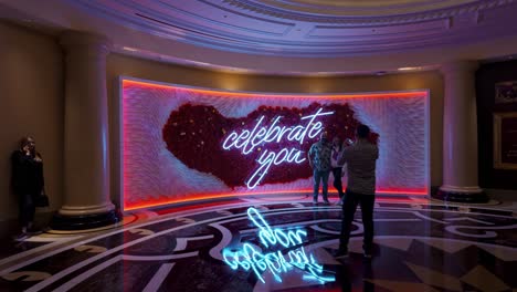 Una-Pareja-Tomando-Fotos-Frente-A-Una-Gran-Pared-De-Celebración-Dentro-Del-Hotel-Venetian-En-Las-Vegas