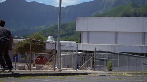 Person,-Die-Auf-Dem-Bürgersteig-In-Hawaii-Mit-Großen-Bergen-Skateboard-Fährt