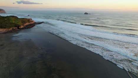 Wellen-Plätschern-Am-Muriwai-Strand-Bei-Sonnenuntergang-Mit-Der-Insel-Oaia-In-Der-Ferne