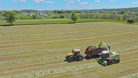 Ein-Claas-Traktoren-Arbeiten-In-Harmonie,-Pressen-Heu,-Wenn-Der-Tag-Zu-Ende-Geht,-Und-Verwandeln-Felder-In-Ordentlich-Organisierte-Linien-Unter-Azurblauem-Himmel