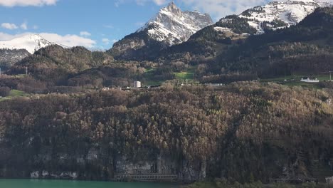 Aerial-perspective-reveals-the-scenic-snow-capped-mountain-peaks-of-Wessen,-Schweiz,-encircled-by-forests-below,-untouched-by-snow,-showcasing-the-contrast-of-elevations-in-mountainous-terrain