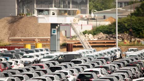 Vast-car-parking-lot-filled-with-new-vehicles-near-industrial-railway-tracks