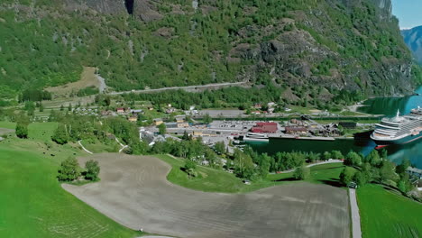 Cruise-ship-docked-at-Flam,-Norway-port---aerial-parallax-town-and-countryside