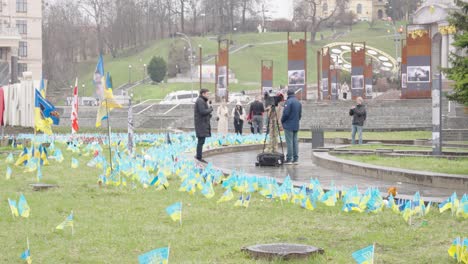 Reporter-at-Independence-Square-in-city-center-as-blue-yellow-flags-wave-on-rainy-day