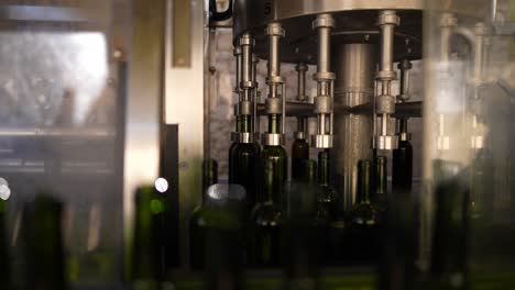 Green-glass-wine-bottles-filling-up-at-an-automated-production-line-in-Vignonet-France,-Medium-shot