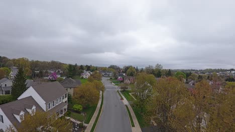 Forward-flight-over-Suburb-Neighborhood-with-homes-and-buildings-during-grey-cloudy-day-in-America