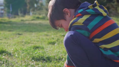 Close-up-side-view-of-caucasian-cute-boy,-playing-with-soil-in-his-hands-at-the-fields-on-a-sunny-day-outdoors