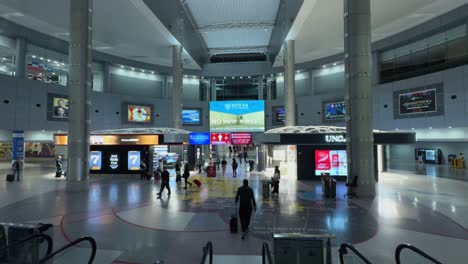 Descending-escalator-view-inside-Newark-Airport,-capturing-a-spacious-terminal-with-travelers,-advertisements,-and-modern-architecture