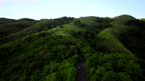 Scooter-drives-through-lush-forested-area-up-Teletubbies-Hills,-Bali