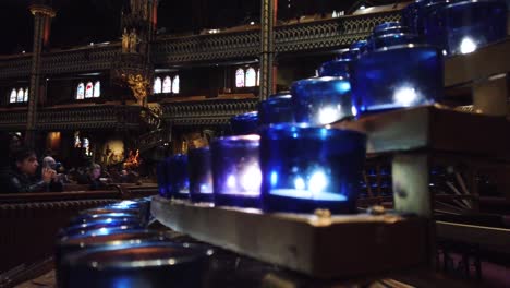 Shot-of-the-candles-and-people-praying-at-the-main-altar-of-the-Notre-Dame-Cathedral-in-Montreal,-Canada