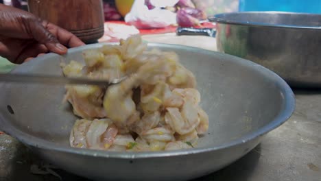 Shrimps-preparation-in-grey-steel-pot,-black-hand-stirs-with-big-spoon
