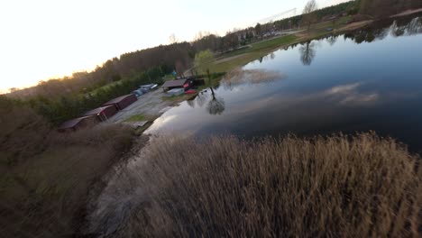 Disparo-De-Drones-FPV-Volando-Sobre-Juncos-Y-La-Superficie-De-Un-Lago-Reflejado-En-Un-Día-De-Primavera