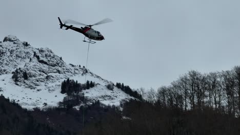 Helicopter-conducting-operations-over-snowy-mountain-terrain-near-Walensee,-Switzerland,-showcasing-a-dramatic-winter-landscape