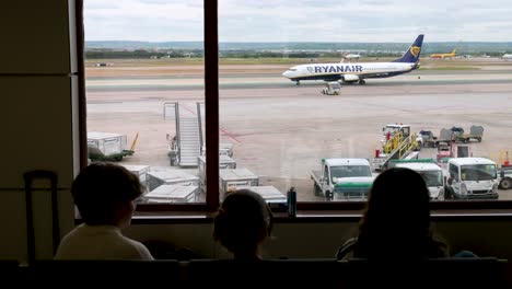 Los-Pasajeros-Del-Vuelo-Están-Sentados-En-La-Zona-De-Espera-Como-La-Aerolínea-De-Bandera-De-La-Aerolínea-Irlandesa-De-Bajo-Coste-Ryanair.-Taxis-En-La-Pista-Del-Aeropuerto-Adolfo-Suárez-De-Madrid-Barajas-En-Madrid,-España.