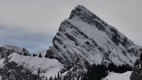 Kreisende-Drohnenaufnahme-Eines-Großen-Berggipfels,-Der-Im-Winter-Mit-Einer-Dünnen-Schneedecke-Bedeckt-Ist