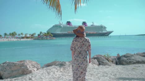 Woman-wearing-a-hat-and-a-dress-looking-sea-and-cruise-on-beautiful-sea-slow-backshot