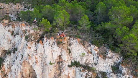 Couple-picnic-on-cliff-edge-with-a-view-of-the-green-landscape-during-sunset-in-ibiza