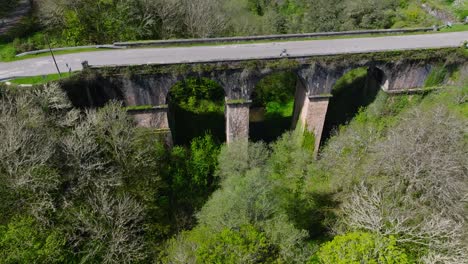 Puente-Cruzul-Sobre-El-Río-Narón-Con-Follaje-Cubierto-De-Maleza-En-Becerrea,-Lugo,-España