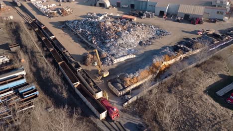 Industrial-scrapyard-in-hamilton,-ontario,-with-excavator-and-train,-aerial-view