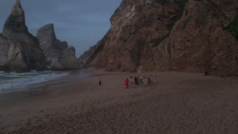 Grupo-De-Mujeres-Felices-Bailando-Descalzas-En-La-Playa-De-Arena-En-Portugal-Durante-El-Día-Nublado