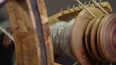 Close-up-artisan-prepares-yarn-spool-on-antique-Nordic-spinning-wheel