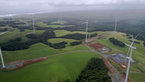Aerial-of-renewable-energy-wind-farm-turbines-and-green-forest-on-cloudy-day,-Tasmania,-Australia