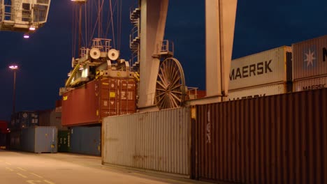 Toma-Nocturna-De-Una-Concurrida-Terminal-De-Contenedores-Con-Grúas-Y-Carga-Apilada.