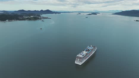 Circular-drone-shot-of-a-cruise-ship-sailing-near-the-mainland-in-Babitonga-bay,-Santa-Catarina